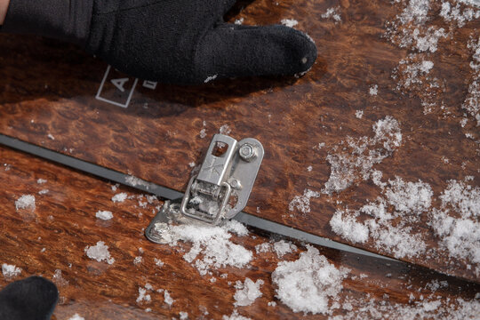 Hands assembling a snow covered backcountry splitboard
