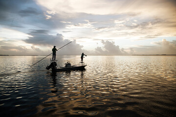 A woman casts her fly line from a boat in the florida keys at sunset