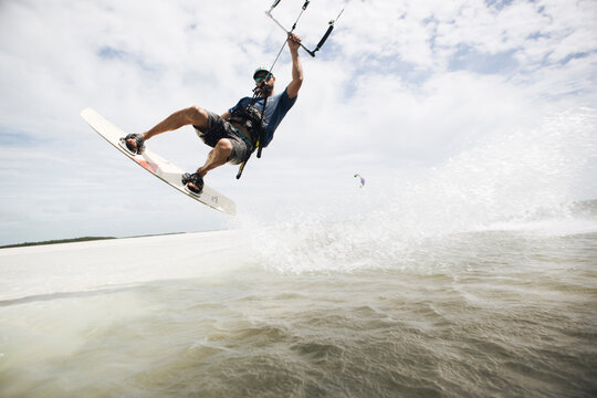 A man kiteboarding in the florida keys jumps out of the water