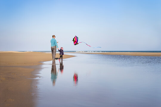 Father and daughter fly kite at beach in winter