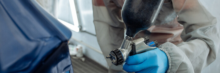 Banner . automobile repairman painter hand in protective glove with airbrush pulverizer painting...