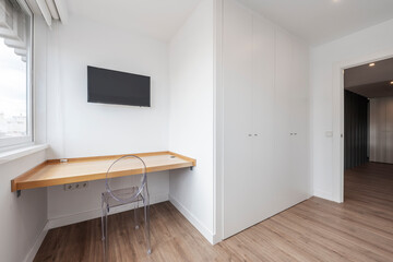 Room with desk, small plasma TV, white built-in wardrobe and oak parquet floors