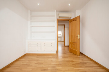 Living room with plaster cabinet with wooden shelves and drawers with oak parquet floors