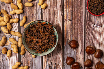 Obraz premium Top view image of bowl full of star anise, chestnuts and peanuts on wooden table