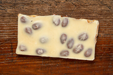 piece of white chocolate with almonds on a rustic wooden table