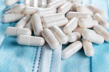 Pharmaceutical white capsules on hygienic medical blue masks. Macro