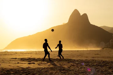 Photo sur Plexiglas Rio de Janeiro Two Brothers Mountain behind 2 friends playing soccer at Ipanema Beach, Rio de Janeiro. Sunset at summer