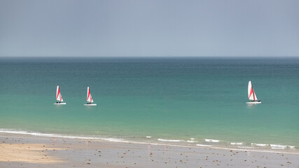 Beautiful beach at Agon-Coutainville in Normandy, with a sailing boat on the sea
