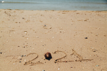 Text 2021 Written on the Sand of a Beach. The Sea on a Background of Letters