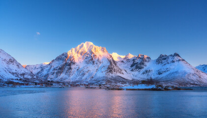 Belles montagnes couvertes de neige et ciel bleu reflété dans l& 39 eau au coucher du soleil. Paysage d& 39 hiver avec mer, rochers enneigés, reflet, au coucher du soleil. Îles Lofoten, Norvège au crépuscule. Fond de nature