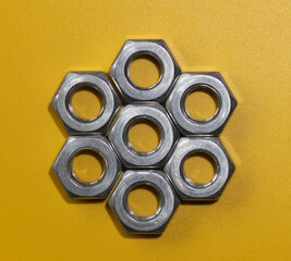 Stainless nuts laid out on a colorful background in a hexagonal shape 