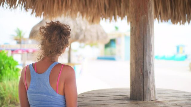 Closeup Of Young Tan Female Woman Girl With Sunburn Skin At Restaurant Straw Tiki Bar Building Table Buying Drinks At Island Beach Resort Happy Smiling