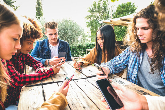 Group of friends checking social media on smartphones at restaurant or pub and ignoring each other -  Leisure, technology and people concept