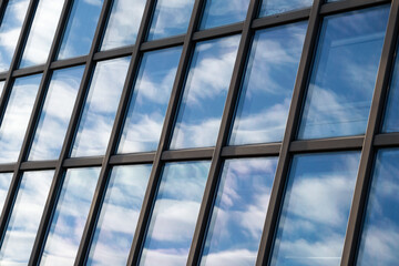 Sky and clouds reflection in the windows of modern building. Building exterior, glass