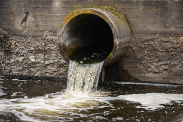 Dirty water flows from the pipe into the river, environmental pollution. Sewerage, treatment...