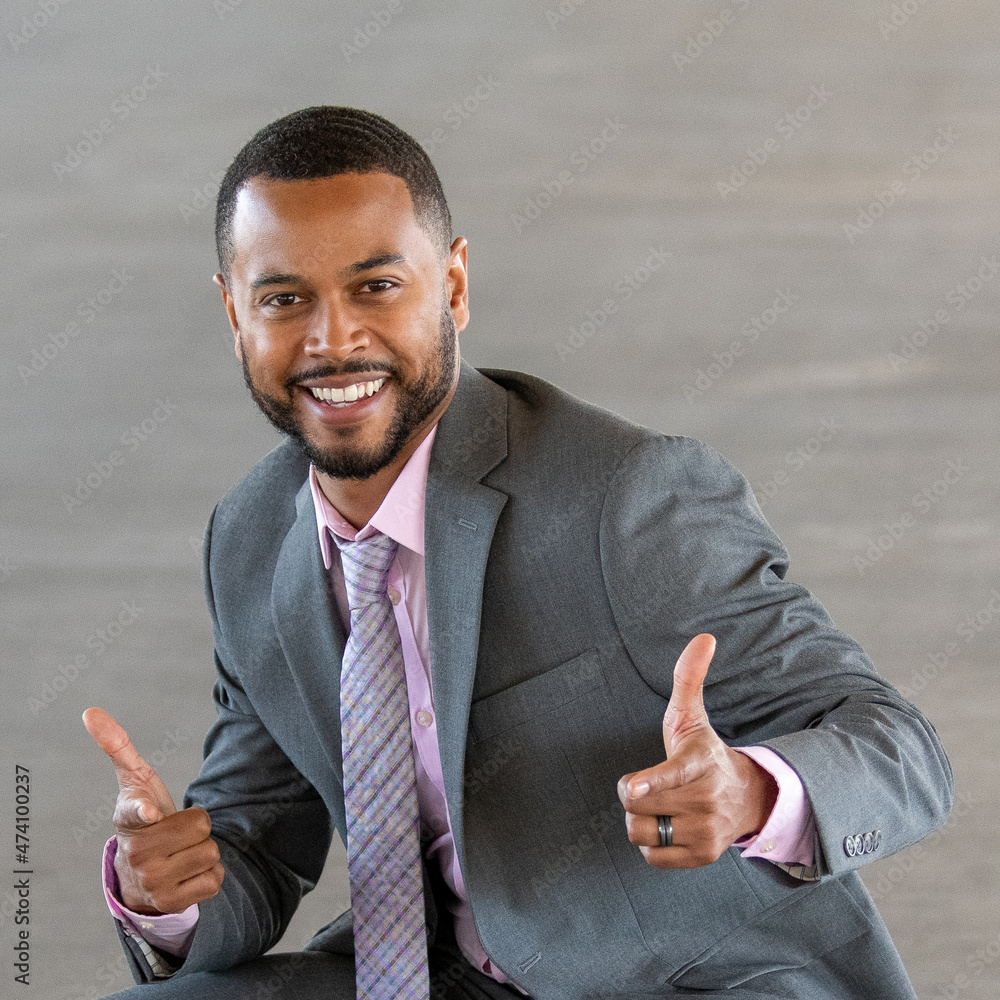 Wall mural multi racial athletic business man wearing grey suit with pink tie smiling and giving thumbs up