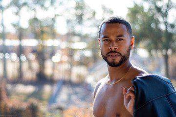 Multi-racial athletic fit male shirtless holding leather jacket