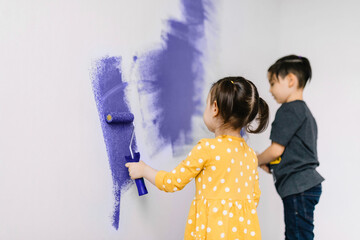 Children paint the wall in a fashionable color Very Peri - the color of 2022