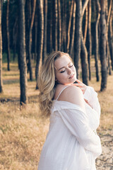 Fototapeta na wymiar plus size girl in a pine forest at sunset in a white femine sundress