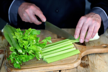 Selective focus. The cook cuts celery sticks with a knife. Fresh celery.
