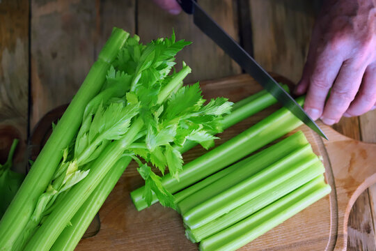 Selective focus. The cook cuts celery sticks with a knife. Fresh celery.