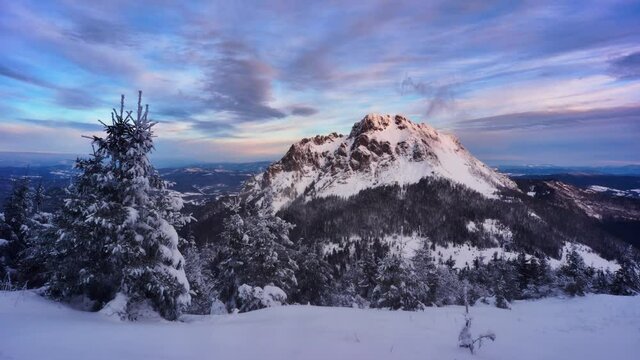 Winter sunrise over snowy mountains Clouds spill over the mountain windy weather