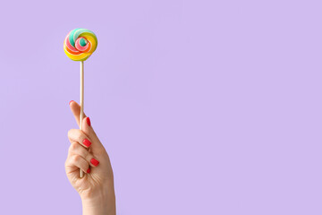 Woman holding lollipop on lilac background