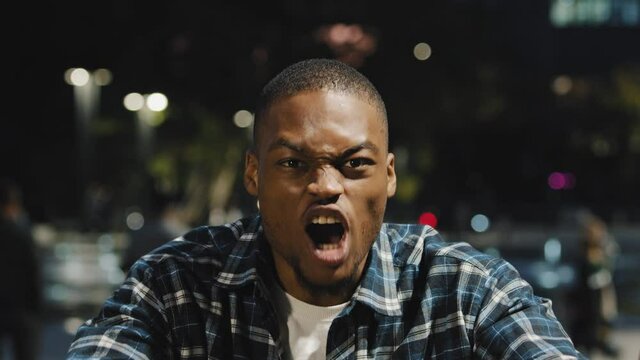 Close-up male agressive face african american guy man shouts cheering for team upset frustrated disappointed worried screams anger stressed standing in evening at night in city outdoors face emotions