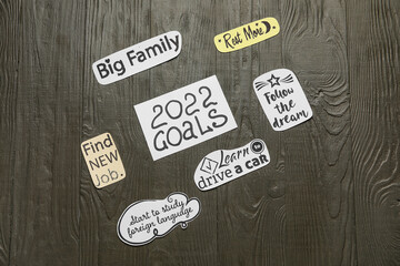 Paper sheets with to do list and text 2022 GOALS on dark wooden background