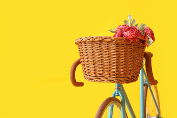 Fototapeta na wymiar Modern bicycle with wicker basket and peony flowers on yellow background