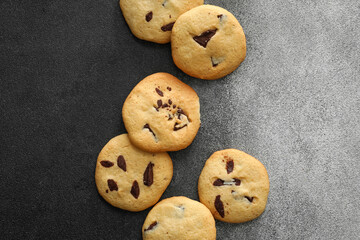 Tasty homemade cookies with chocolate chips on dark background