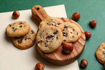 Board with tasty homemade cookies and chestnuts on color background