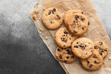 Parchment with tasty homemade cookies on grey background