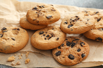 Parchment with tasty homemade cookies on table, closeup