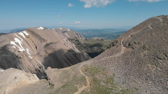 Fly around rocky peak to reveal mountain ridge 