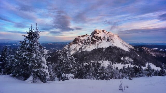 Winter sunrise over snowy mountains Clouds spill over the mountain windy weather