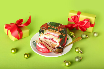 Plate with tasty bento cake, gifts and Christmas decor on color background