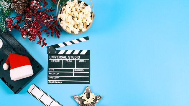 Retro videotape, cracker, popcorn in a craft basket, santa hat and spruce branch on the left.