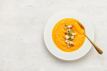 Plate of tasty pumpkin cream soup on white background