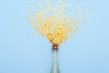Composition with champagne bottle and golden confetti on color background