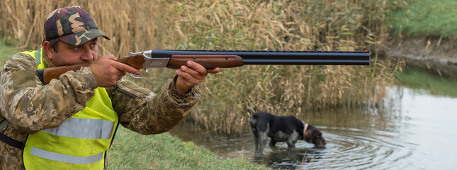 Hunter man in camouflage with a gun during the hunt in search of wild birds or game. Autumn hunting...