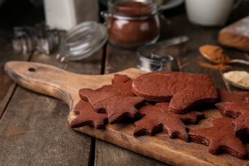 Board with tasty chocolate Christmas cookies on wooden background, closeup