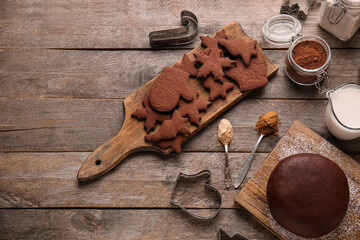 Fototapeta na wymiar Boards with tasty chocolate Christmas cookies and dough on wooden background