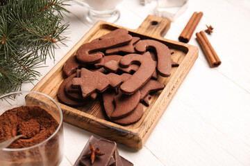 Board with tasty chocolate Christmas cookies and ingredients on white wooden background