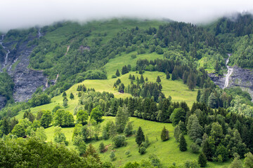 Fototapeta na wymiar Panoramic view on mountain waterfalls, green forests and apline meadows near Saint-Gervais-les-Bains, Savoy. France