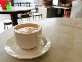 Tea with milk in a cup locally popularly known as Teh Tarik on the table.