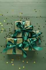 Beautiful Christmas gifts and confetti on green wooden background