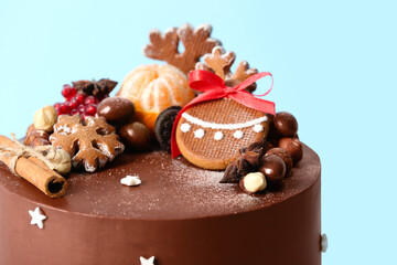 Tasty Christmas chocolate cake on blue background, closeup