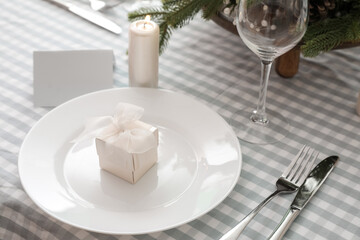 Plate with gift box and cutlery on dining table decorated for Christmas celebration, closeup