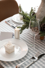 Plate with gift box and cutlery on dining table decorated for Christmas celebration